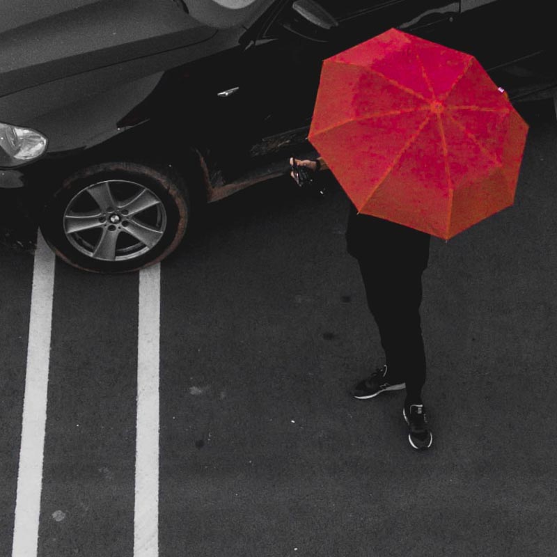 anonymous person in black under red umbrella