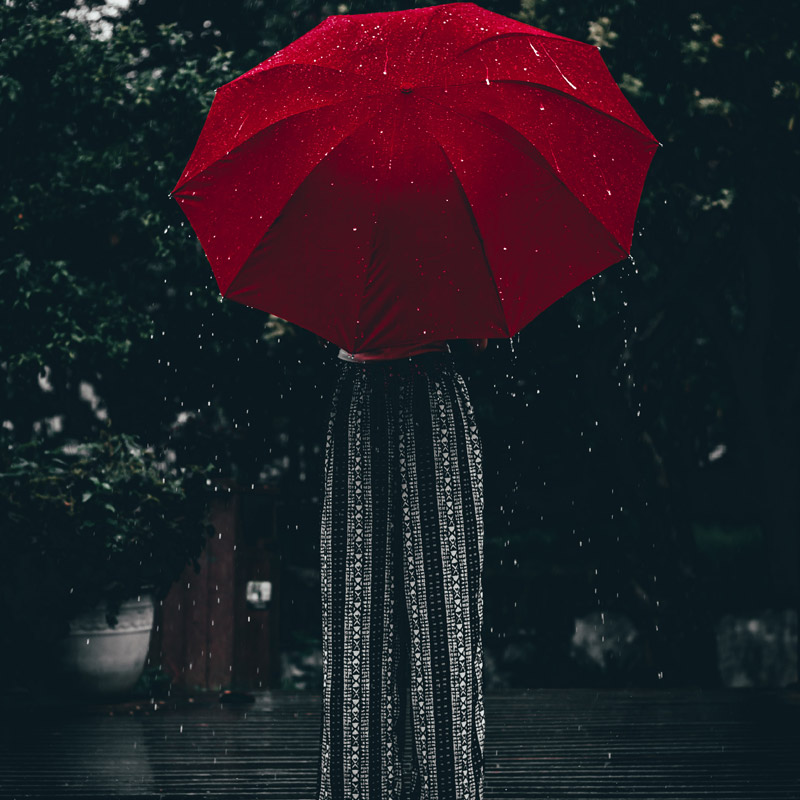 red umbrella held by person in black dress